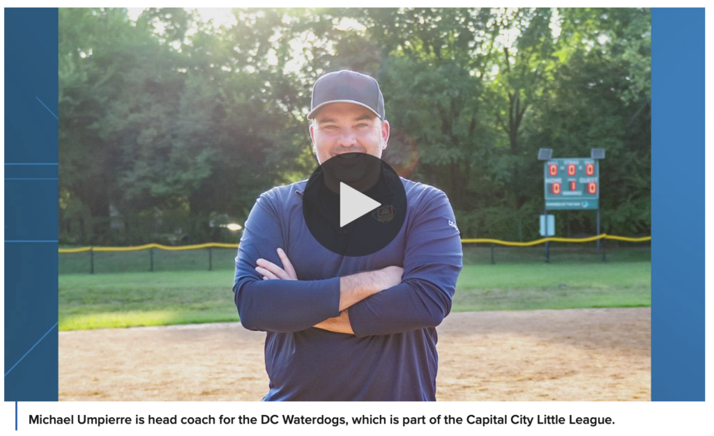 Coach Mike with baseball hat and arms crossed, smiling.