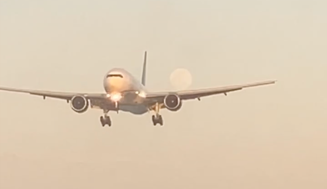 plane landing with moon behind it.